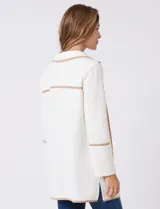 Chaqueta de silueta estructurada y calce recto, confeccionada en tejido jacquard con relieve floral. Presenta cuello con solapas, frente abierto y dos bolsillos de parche frontales. Se destaca por sus vivos a contratono que bordean las solapas, los bolsillos y las costuras horizontales, además de contar con tajos laterales en el ruedo.