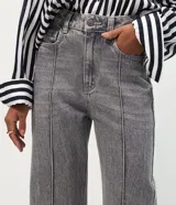 Pantalón wide leg de tiro alto confeccionado en denim de algodón. Presenta un diseño con friso vertical en el frente, cierre de botón y cremallera, trabillas en la cintura y bolsillos funcionales en la parte delantera y trasera.