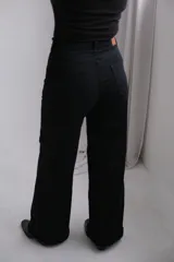 Pantalón de jean negro de corte recto y tiro alto, con cierre frontal de botón y cremallera, y bolsillos laterales.