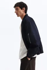 Campera bomber en mezcla de algodón y nylon color azul marino, con cuello elevado acanalado, cierre frontal, bolsillos laterales y un bolsillo con cierre en la manga.