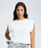 Blusa blanca sin mangas, confeccionada en tejido rib con textura acanalada, cuello redondo y hombreras incorporadas que estructuran los hombros.