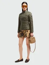 Chaqueta corta tipo puffer de Moncler, color verde oliva, con cuello alto, cierre frontal y diseño acolchado horizontal. Presenta el logo de la marca en la manga izquierda.