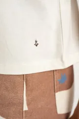 Remera negra de algodón con mangas tres cuartos abullonadas y detalle de bordado calado tipo ojal en la zona del antebrazo.