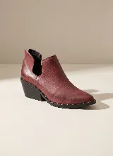Botín de cuero vacuno color bordó, con diseño de abertura lateral y detalle de tachas metálicas en el borde de la suela. Cuenta con taco cuadrado de 5 cm y suela de caucho antideslizante.