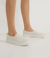 Championes slip-on color beige, sin cordones, con diseño capitoné en la parte frontal y suela blanca de goma.