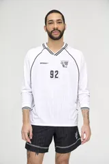 Camiseta de fútbol blanca con cuello en V y mangas largas con puños a rayas negras. Tiene un logo de la marca en el pecho y el número 92 en el centro.
