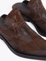 Zueco estilo western de cuero vacuno plateado, con costuras decorativas en la capellada, punta cuadrada y taco bajo de 4 cm.