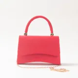 Cartera de mano tipo sobre color rojo, con acabado aterciopelado, asa superior rígida y cadena metálica dorada extraíble.