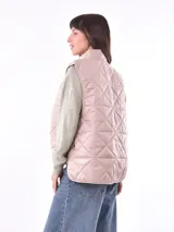 Chaleco acolchado color rosado con diseño de rombos, cuello alto y cierre frontal con botones a presión metálicos.
