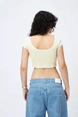 Top corto negro de punto acanalado con escote redondo, mangas cortas y ribetes blancos en cuello y mangas.