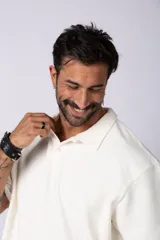 Chomba de manga corta con cuello polo, confeccionada en tejido de punto acanalado de textura pesada. Presenta un calce relajado y cuenta con una pequeña etiqueta distintiva en el ruedo.