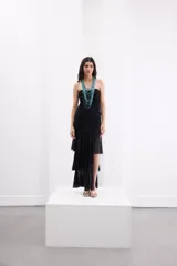 Vestido largo de encaje negro con diseño al cuerpo, escote strapless con breteles removibles, frunces frontales y falda con volados asimétricos.