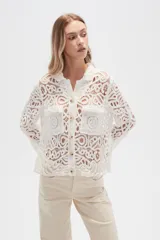 Camisa blanca de crochet con cuello camisero, cierre frontal con botones y dos bolsillos de parche en el pecho.
