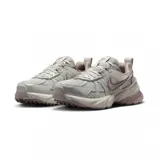 Championes Nike V2K Run de estilo retro-futurista, con diseño en capas de malla y material sintético en tonos beige y gris. Presenta una entresuela robusta con tecnología Cushlon y el logo de Nike en el lateral.