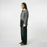 Camisa de corte oversize en color verde con estampado de rayas verticales finas. Presenta cuello clásico y puños en color blanco, cierre frontal con botones y un bolsillo aplicado en el pecho.