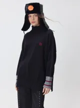 Pullover de punto color rojo, con cuello tortuga, corte holgado y mangas largas con puños acanalados en contraste con rayas blancas. Presenta un logo bordado en el pecho.