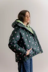 Campera puffer con capucha desmontable, color verde oscuro con estampado de lunares lilas. Cuenta con cierre frontal, bolsillos laterales y forro interno en color verde claro.