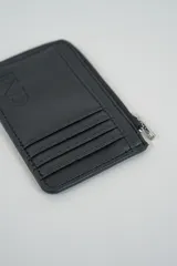 Billetera pequeña color negro con cierre de cremallera plateado y apliques de tachas metálicas redondas en la parte frontal.