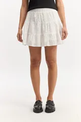 Falda corta blanca con volados en capas, confeccionada en tejido de algodón con bordado estilo broderie. Cuenta con cintura elástica.