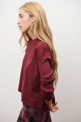 Buzo de punto color beige, con cuello redondo y manga larga.