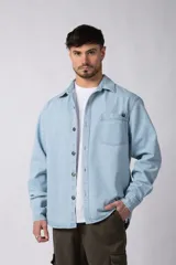 Chaqueta de denim celeste de corte relajado, con cuello clásico, cierre frontal con botones metálicos y un bolsillo aplicado en el pecho.