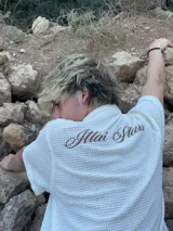 Camisa de waffle color crema con cuello polo, mangas cortas y bordado marrón en la espalda.