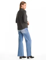 Buzo de tejido fino en color gris oscuro, con cuello alto acanalado y mangas tres cuartos. Presenta un diseño con líneas acanaladas en diagonal desde el cuello hacia las sisas y pequeños tajos laterales en el ruedo.