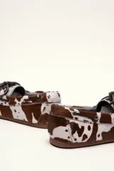 Mocasín tipo boat shoe color marrón, confeccionado en cuero, con cordones de cuero marrón y cordones decorativos azules.