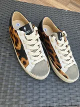 Zapatillas urbanas de cuero vacuno con estampado animal print, puntera de gamuza gris, cordones de algodón crudo y estrella de cuero negro en el lateral.