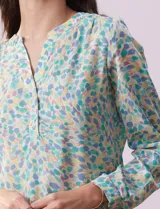 Blusa de gasa estampada con flores, marca Zac & Rachel. Tiene cuello a la base, escote en V y abertura con botones. Las mangas largas son de largo regulable.