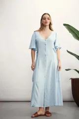 Vestido largo de manga corta, color celeste claro, con escote en V y cierre frontal de botones. Presenta lazos ajustables a los costados a la altura de la cintura.