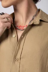 Camisa de manga larga confeccionada en lino, color verde oliva, con cuello clásico y cierre frontal de botones.