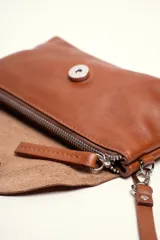 Cartera bandolera color beige, confeccionada en 100% cuero, con solapa redondeada, detalle de flor grabada y correa larga ajustable.