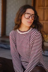 Remera de tejido de punto a rayas horizontales en color marrón y blanco, con cuello redondo, mangas largas y detalle de frunce en el frente.