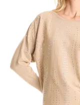 Buzo de tejido fino color beige, con mangas tipo dolman y puños ajustados. Presenta un diseño frontal decorado con apliques de tachas metálicas pequeñas dispuestas en líneas verticales.