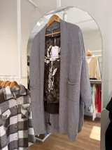 Saco largo abierto de tejido de punto, color gris, con bolsillos delanteros y puños acanalados.