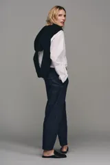 Pantalón chino de tiro bajo color marrón oscuro, con pernera recta y bajo con vuelta. Incluye un cinturón trenzado delgado de color marrón claro. Cuenta con bolsillos delanteros y cierre frontal con cremallera y botón.