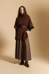 Poncho de tejido de punto color gris, con cuello alto y mangas amplias de diseño holgado.