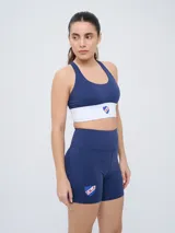 Top deportivo color gris azulado con diseño de espalda natación y el escudo del Club Nacional de Football en el centro.