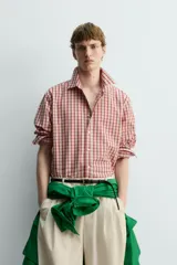 Camisa de algodón con cuello solapa, manga larga terminada en puño con botón y cierre frontal de botonadura. Presenta un patrón de cuadros en tonos rojo y beige.