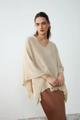 Poncho corto de tejido liviano en color crudo, con escote en V y diseño amplio y fluido.