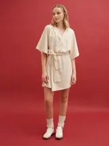 Bata de algodón con diseño envolvente, escote en V, mangas cortas amplias y lazo ajustable en la cintura. Presenta un corte corto y holgado.