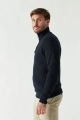 Sweater gris de punto con cuello alto y medio cierre con cremallera. Tiene puños acanalados y logo bordado en el pecho.