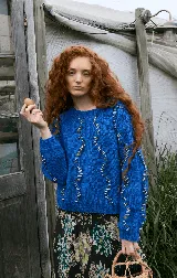 Buzo de lana merino tejido a mano, color azul vibrante, con diseño de ochos tradicionales intervenidos con hilos en contraste que recorren la prenda. Presenta cuello redondo y corte a la cintura.