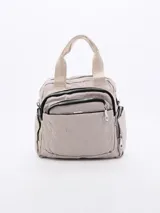 Cartera tipo mochila de color beige, confeccionada en material sintético con diseño acolchado de costuras en forma de V. Cuenta con múltiples compartimentos frontales con cierre, asas superiores y correas ajustables para llevar en la espalda.