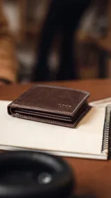 Billetera de cuero marrón con costuras blancas, diseño plegable, doble visor, tarjeteros y doble repartición para billetes.