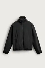 Campera relaxed fit confeccionada en tejido técnico color negro, con interior de borreguillo. Tiene cuello alto, manga larga, bolsillos con cierre de cremallera en la cadera, y acabados elásticos en puños y cintura. Cierre frontal de cremallera.