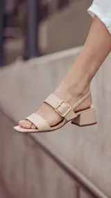 Sandalia de cuero color beige con taco cuadrado de 4 cm, tiras delanteras, tira ajustable con hebilla metálica dorada y tira elástica trasera.
