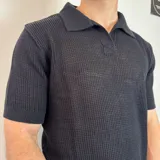 Chomba de tejido de punto con textura, color beige, de manga corta y cuello polo con cierre frontal parcial.