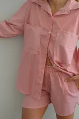 Camisa a rayas rojas y blancas de manga larga, con cuello clásico y corte holgado.